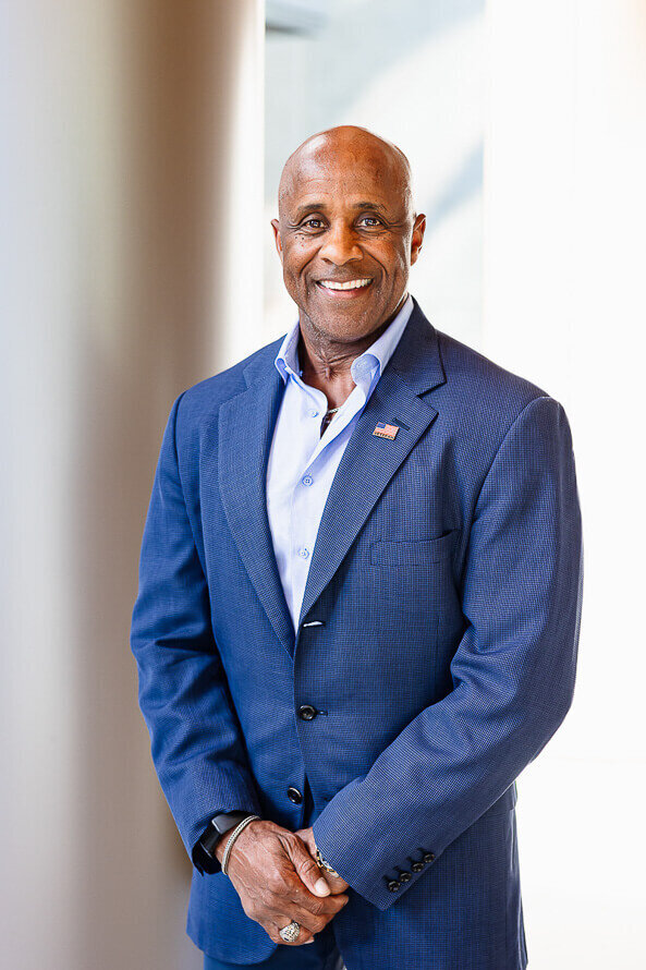 Man poses for his headshot outside next to a white column.