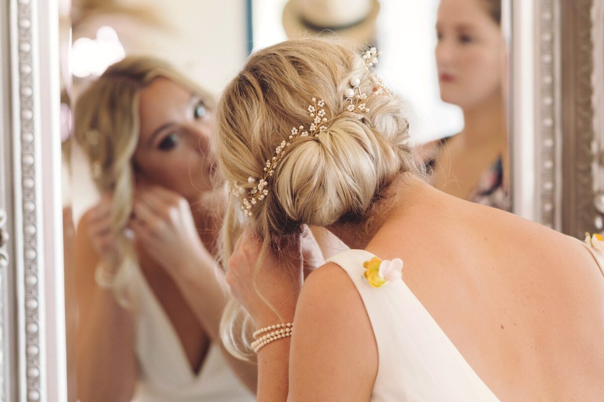 Bride putting on ear rings at wedding in Riviera maya