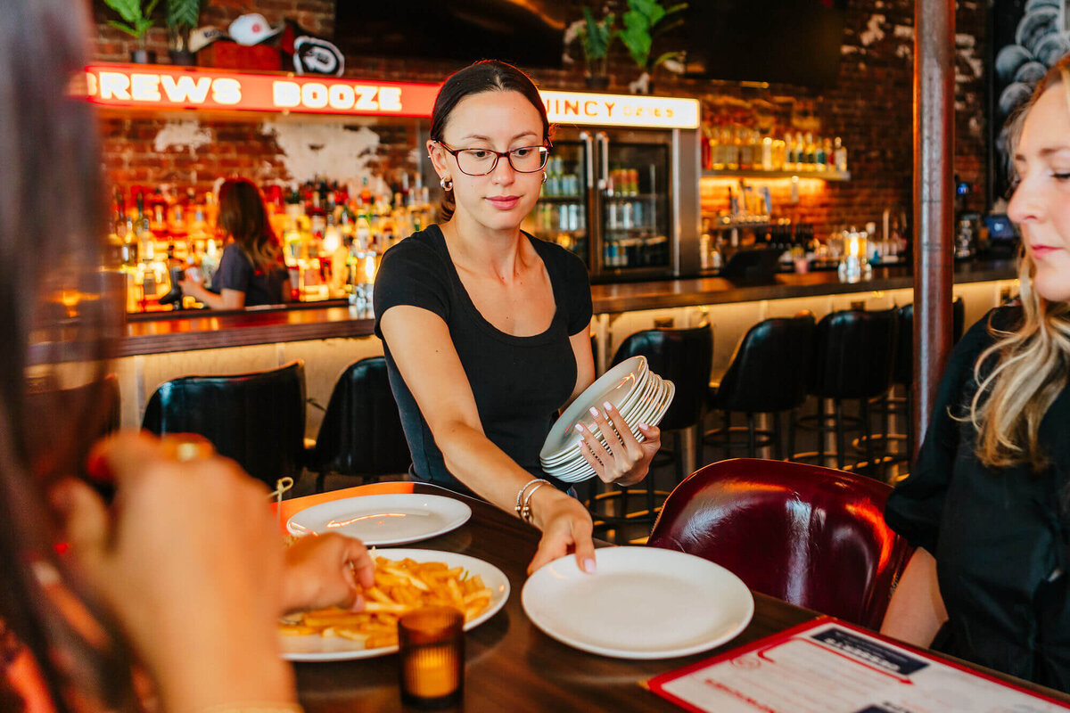 drifter's server delivering appetizer plates to a table of friends