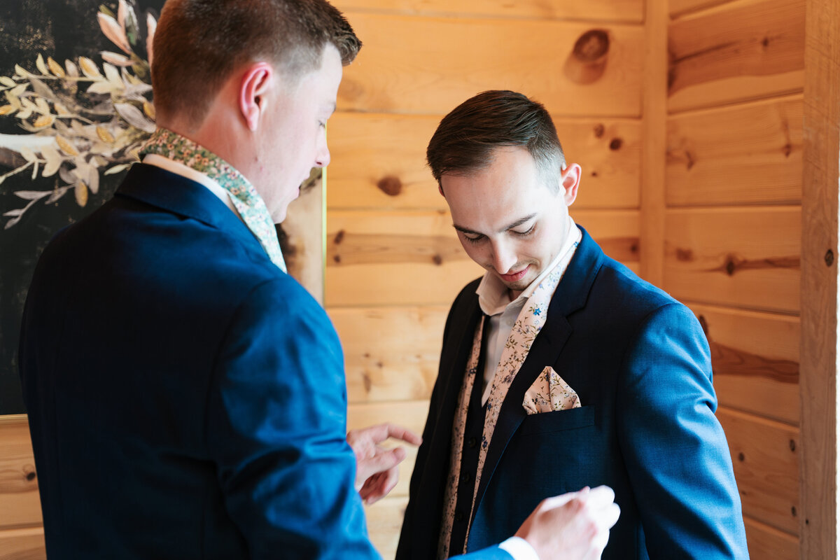 Candid moment of the groom adjusting his tie before the ceremony