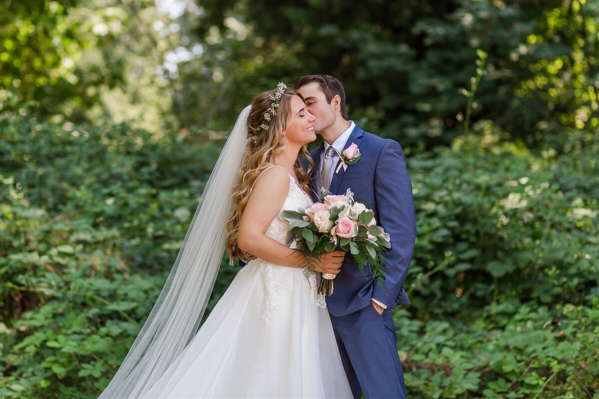 Bride-and-groom-kiss-in-the-forest-at-Snohomish-WA-wedding-Twin-Willow-Gardens-photo-by-Joanna-Monger-Photography