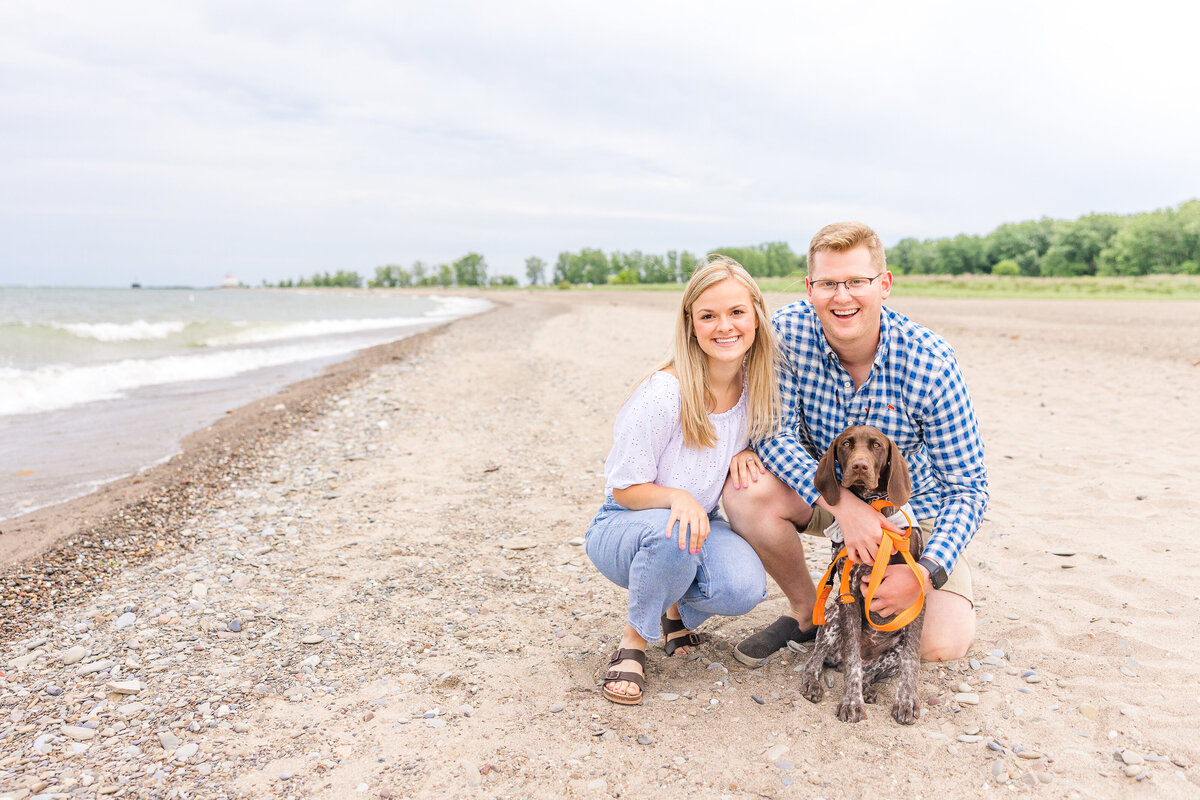 Light and airy beach engagement session in the sand with puppy summer at Mentor Headlands Beach