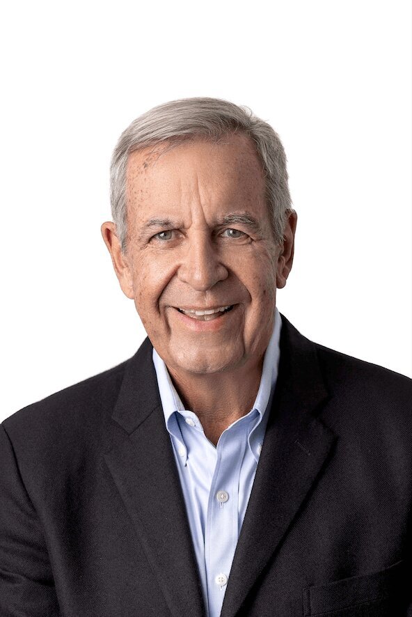 CEO Headshot of a man wearing a suit without a tie on a white background smiling at the camera