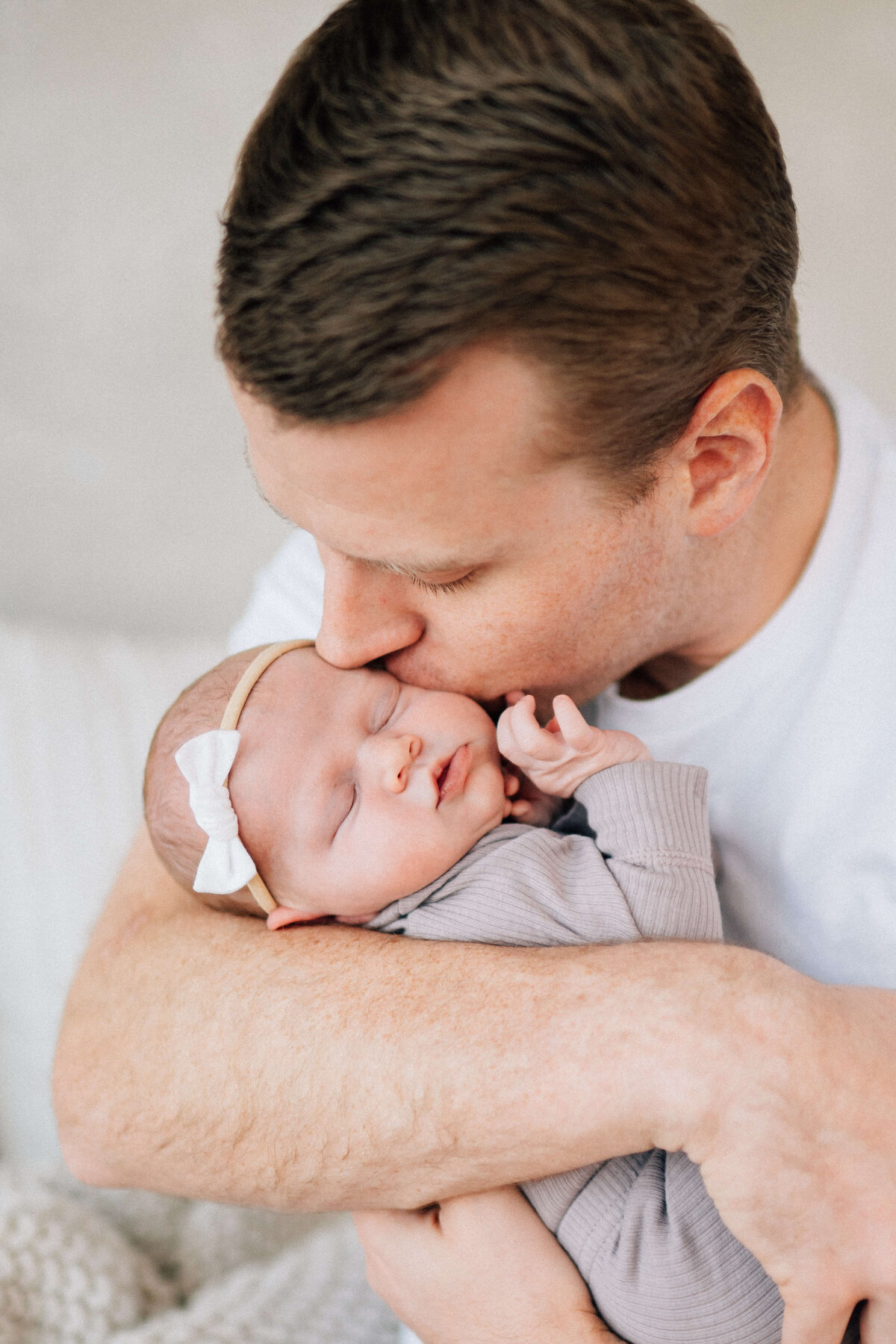 newborn in dad's arms with her hand up touching his face