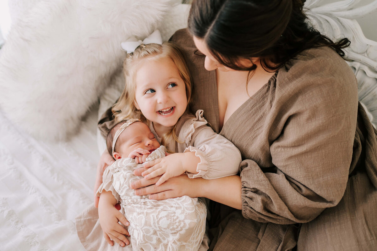 mom cuddling toddler and newborn girl during Springfield Mo newborn photography session