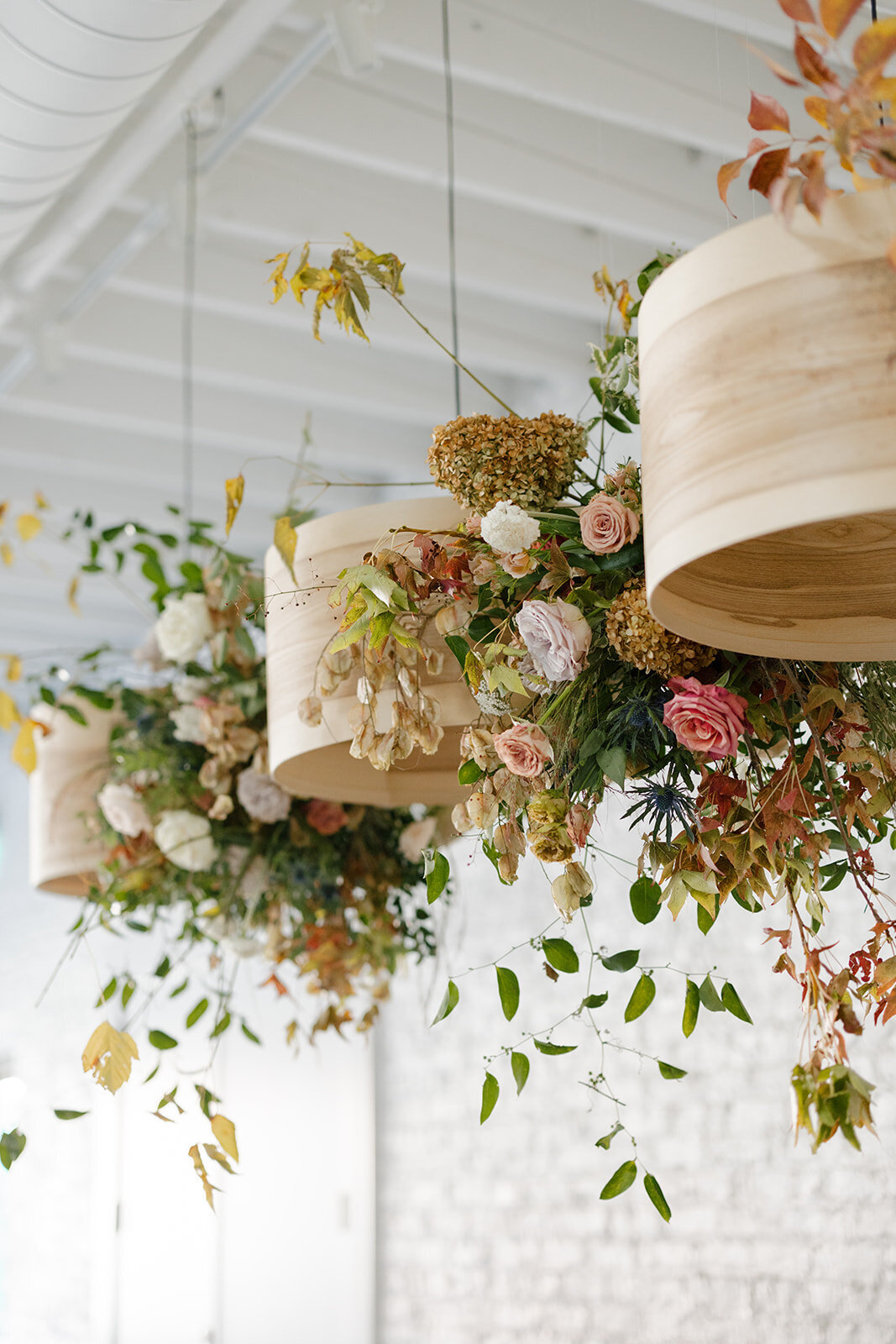 Floral Chandelier hanging floral clouds accent fall wedding reception in Raleigh, NC with roses, hydrangeas, and fall branches in colors of mauve, copper, cream, dusty pink, and green. Design by Rosemary and Finch Floral Design in Nashville, TN.