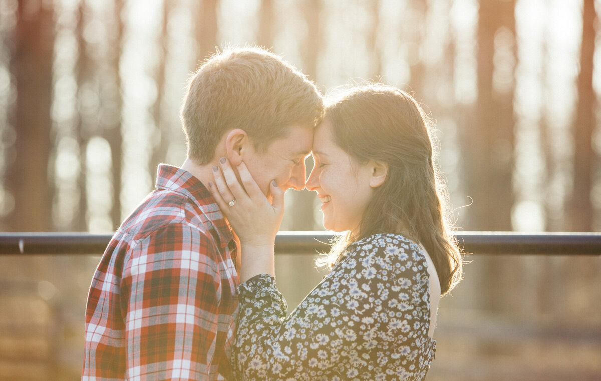 Engaged couple smiling at each other with eyes closed going in for kiss