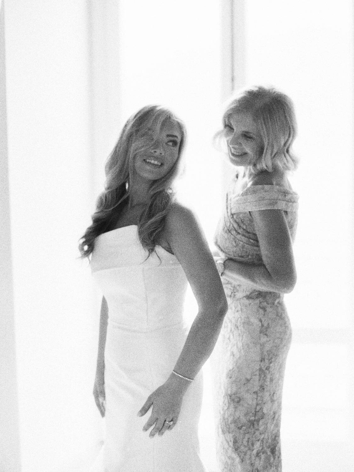 Bride with her mother putting on the dress