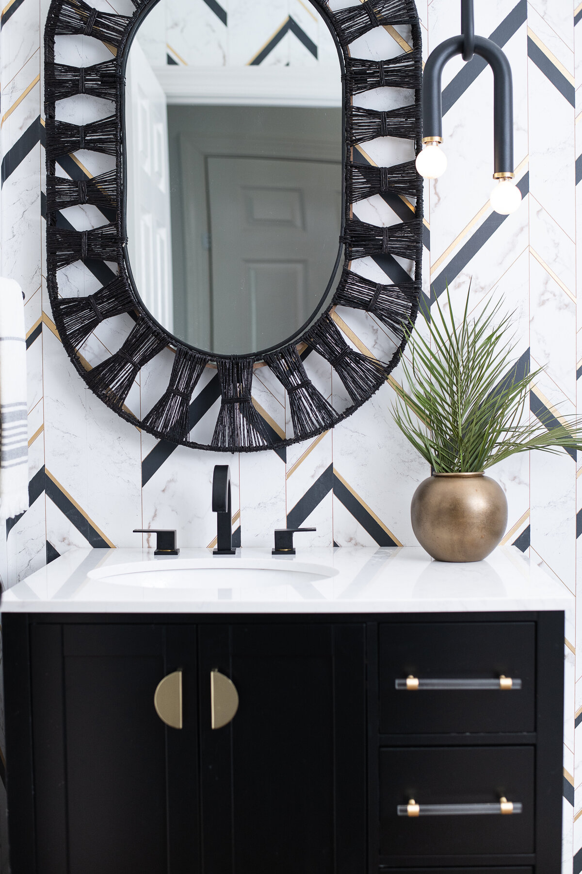 a bathroom with geometric tile on the wall, a white marble sink, and black cabinets