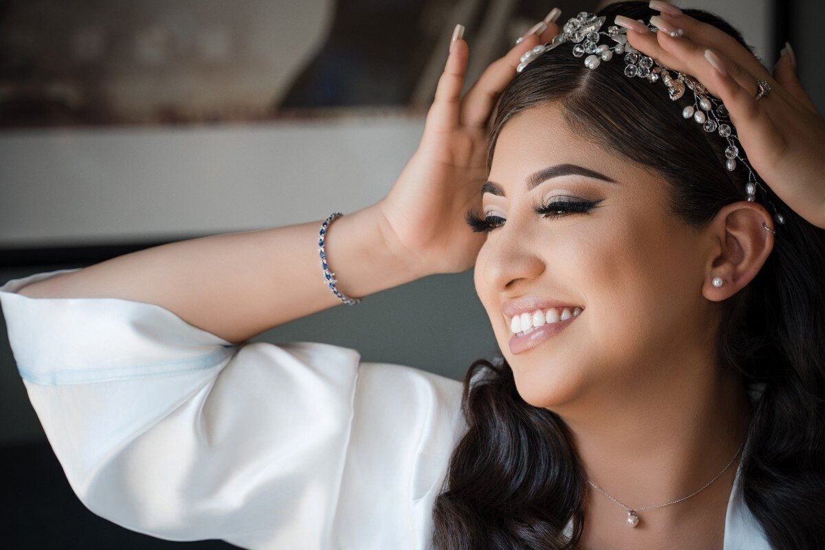 Bride smiling and adjusting her jeweled headpiece during bridal prep at The Union Club Hotel at Purdue University.