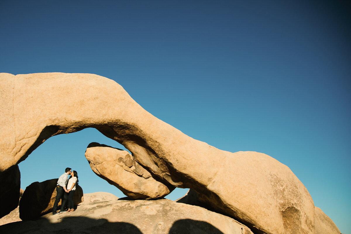 Man and Woman kiss under big arched rocks