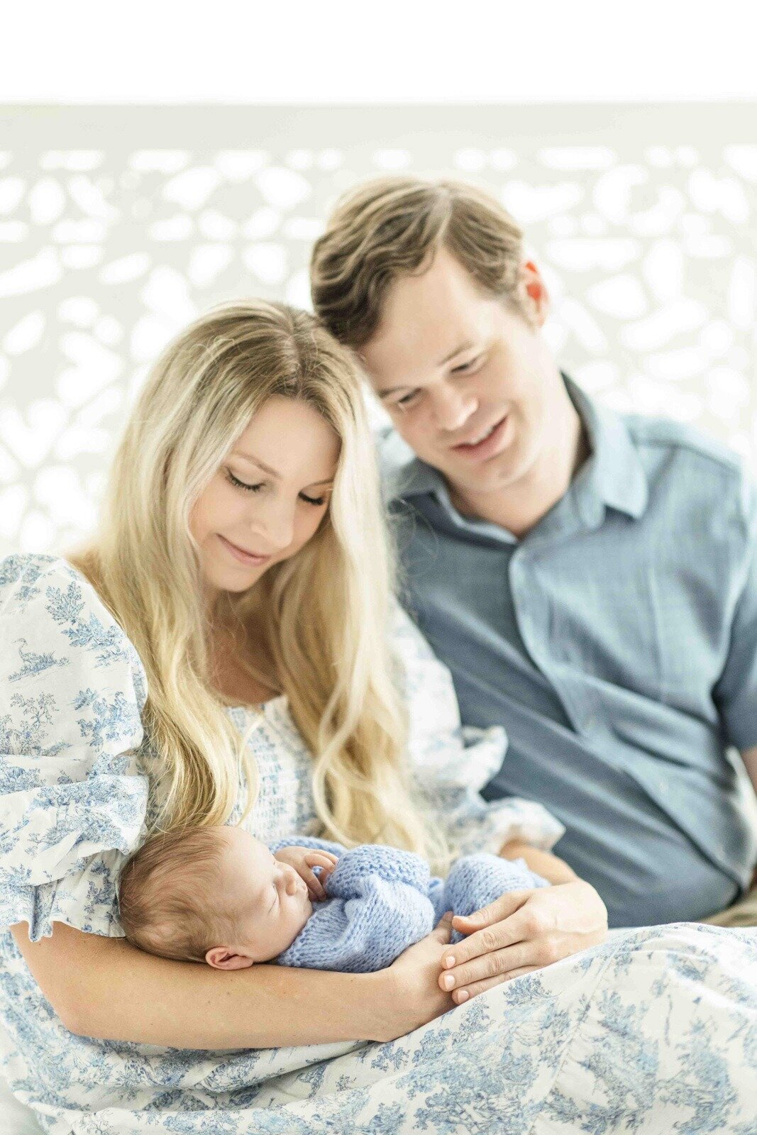 mom dad and newborn baby snuggled together on bed in houston studio 