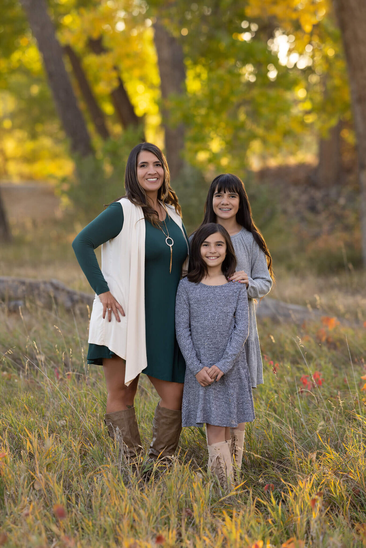 mom and two daughters standing together in a field