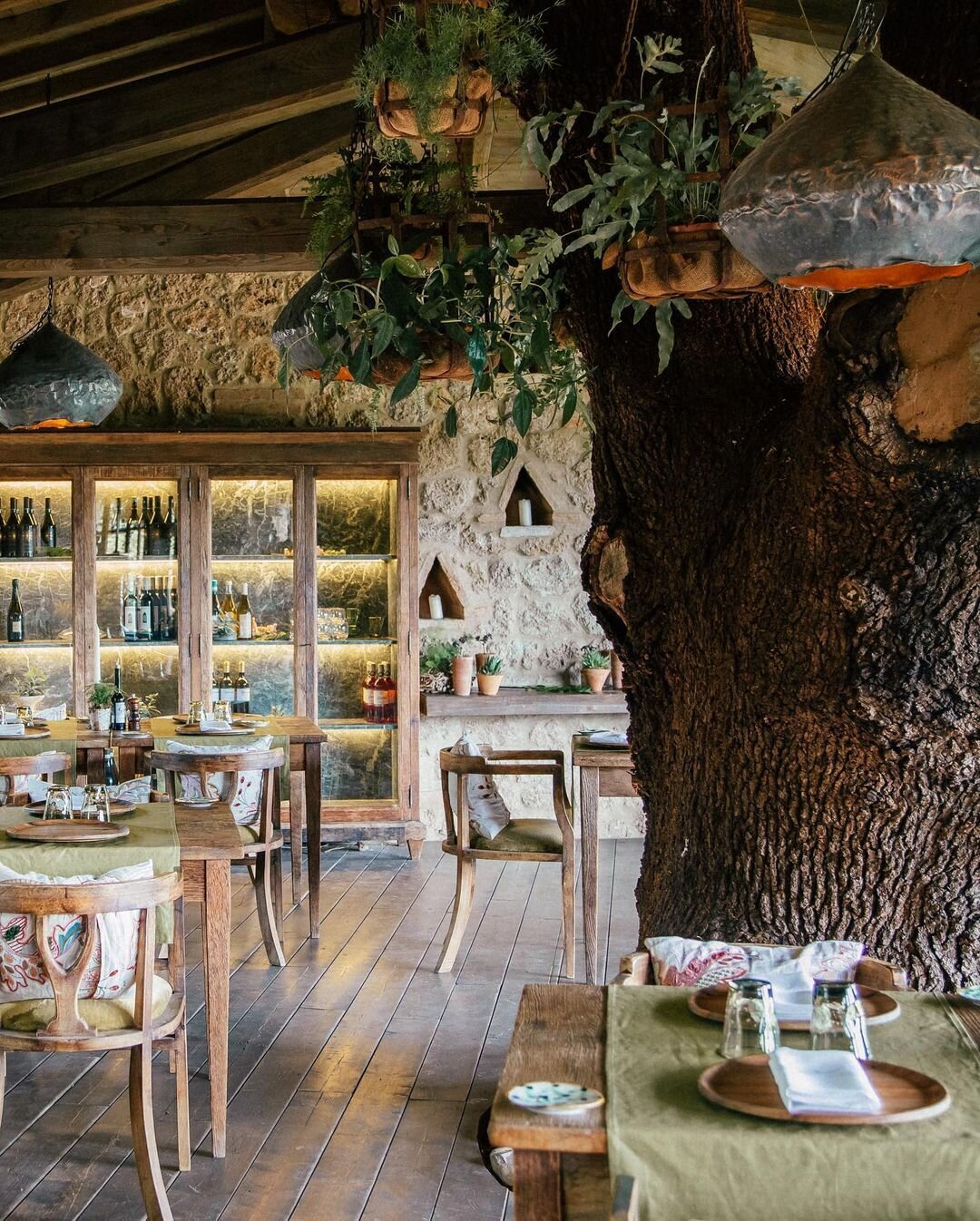The treehouse restaurant at Borgo Santo Pietro with wooden furniture and olive green linen table runners