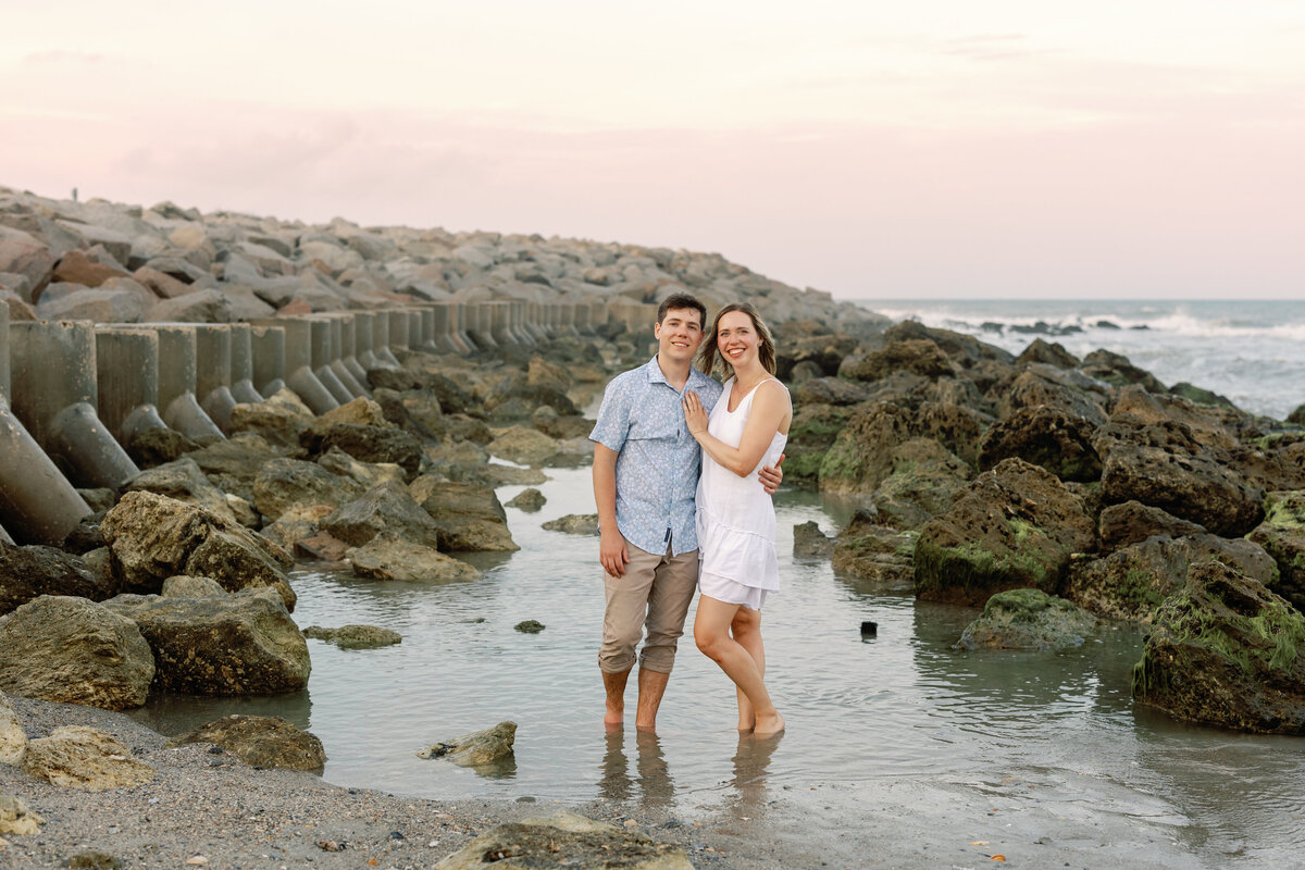 Engaged couple laughing together on Wilmington shoreline, natural engagement portrait