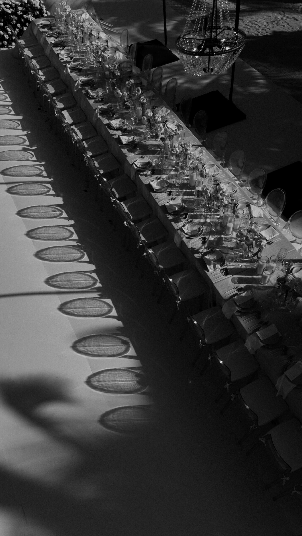 Black and white photo of a Tulum wedding tablescape with beautiful rounded shadows of the chair backs