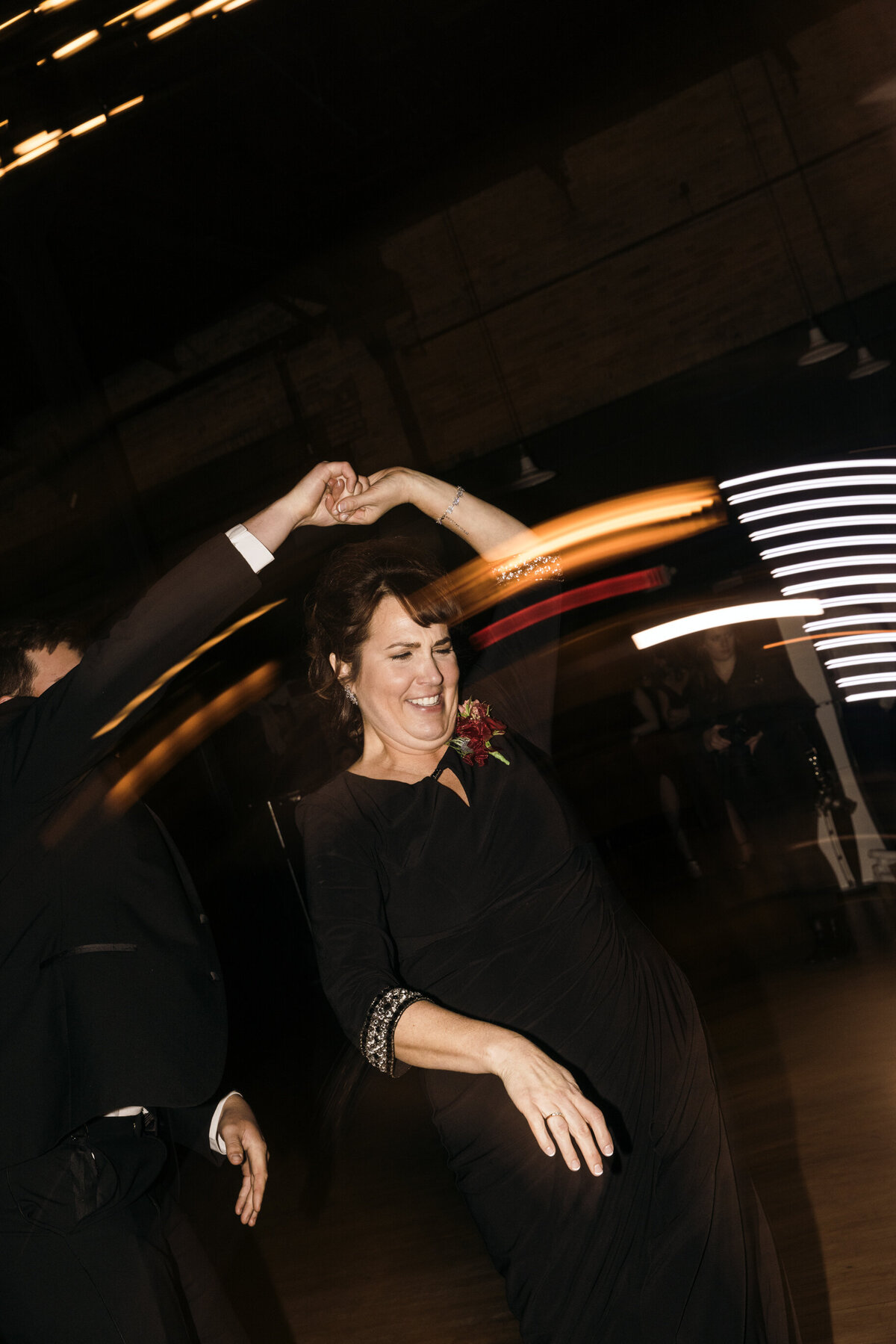 smiling mother of groom twirling during their first dance