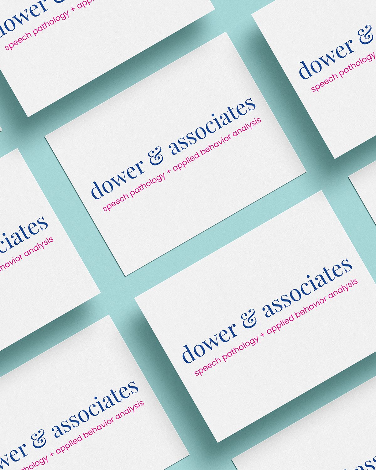 Multiple business cards laid out on a light blue surface showcase the brand design by Sweet Pea Ink Creative, featuring the “dower &amp; associates” logo and the tagline “speech pathology + applied behavior analysis.”.