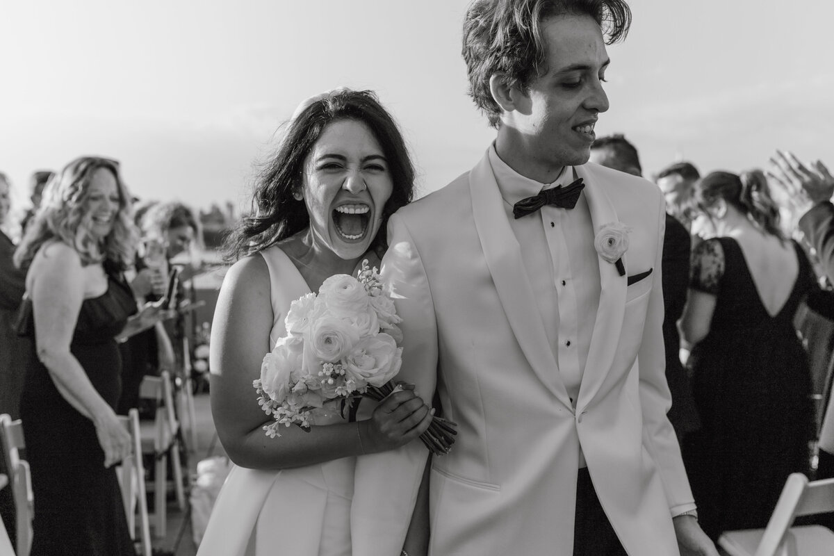 happy couple walking down the aisle on their wedding day, smiling at the camera