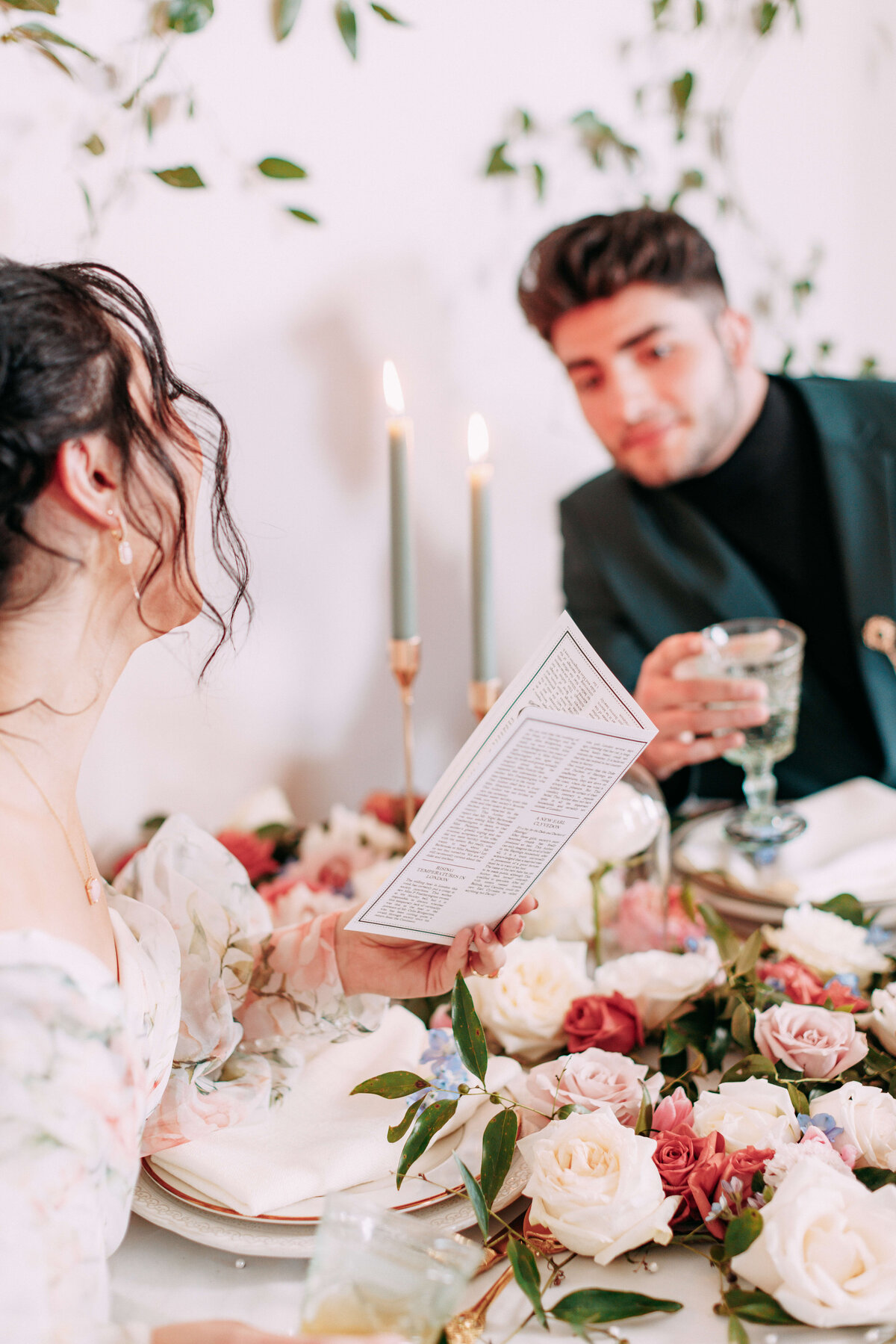 bride and groom reading menu at table with florals and glassses