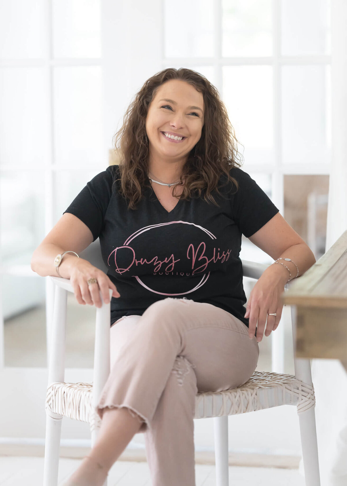 boutique owner in chair in light and airy room smiling as she talks about her featured business