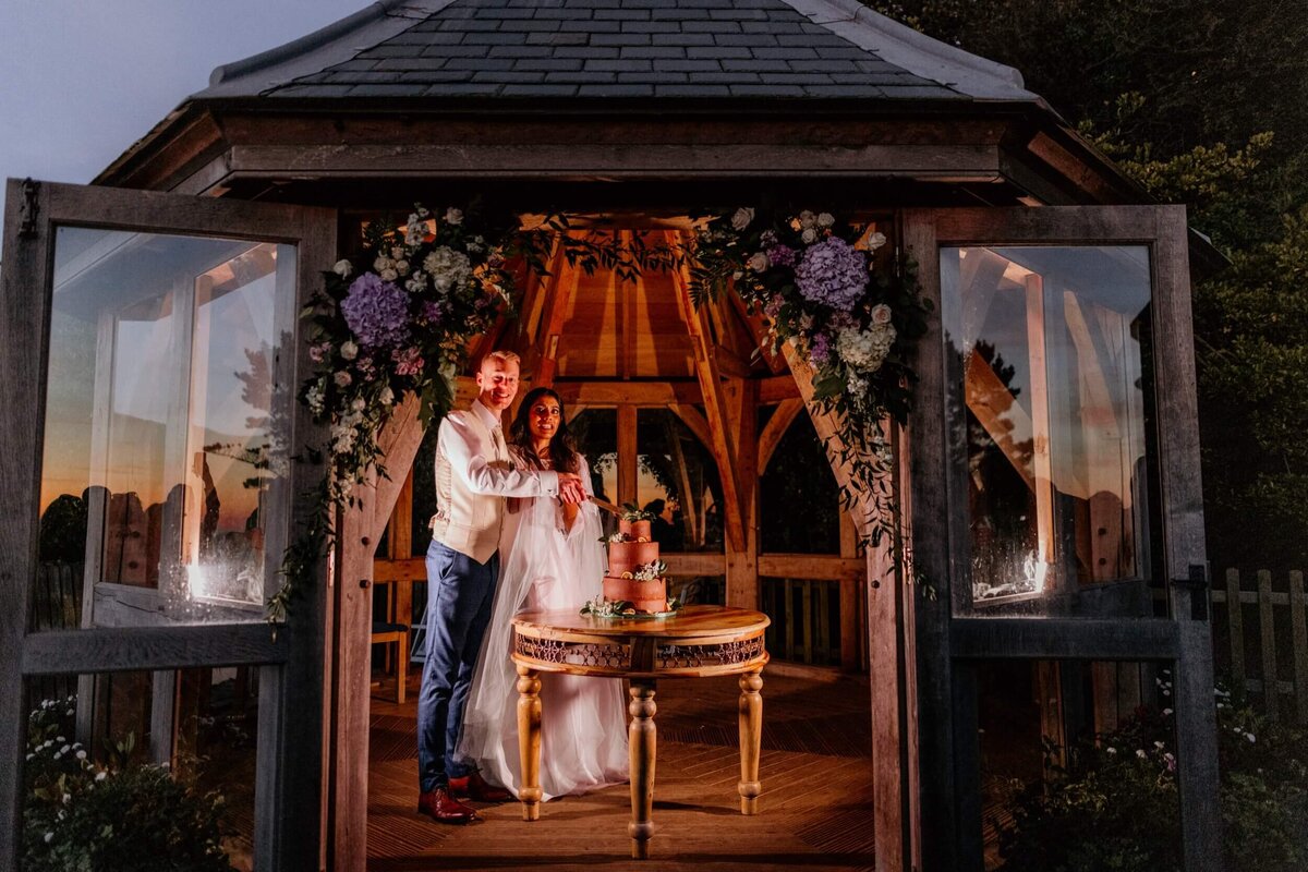 A beautiful shot of the gaxebo with e couple about to cut their wedding cake