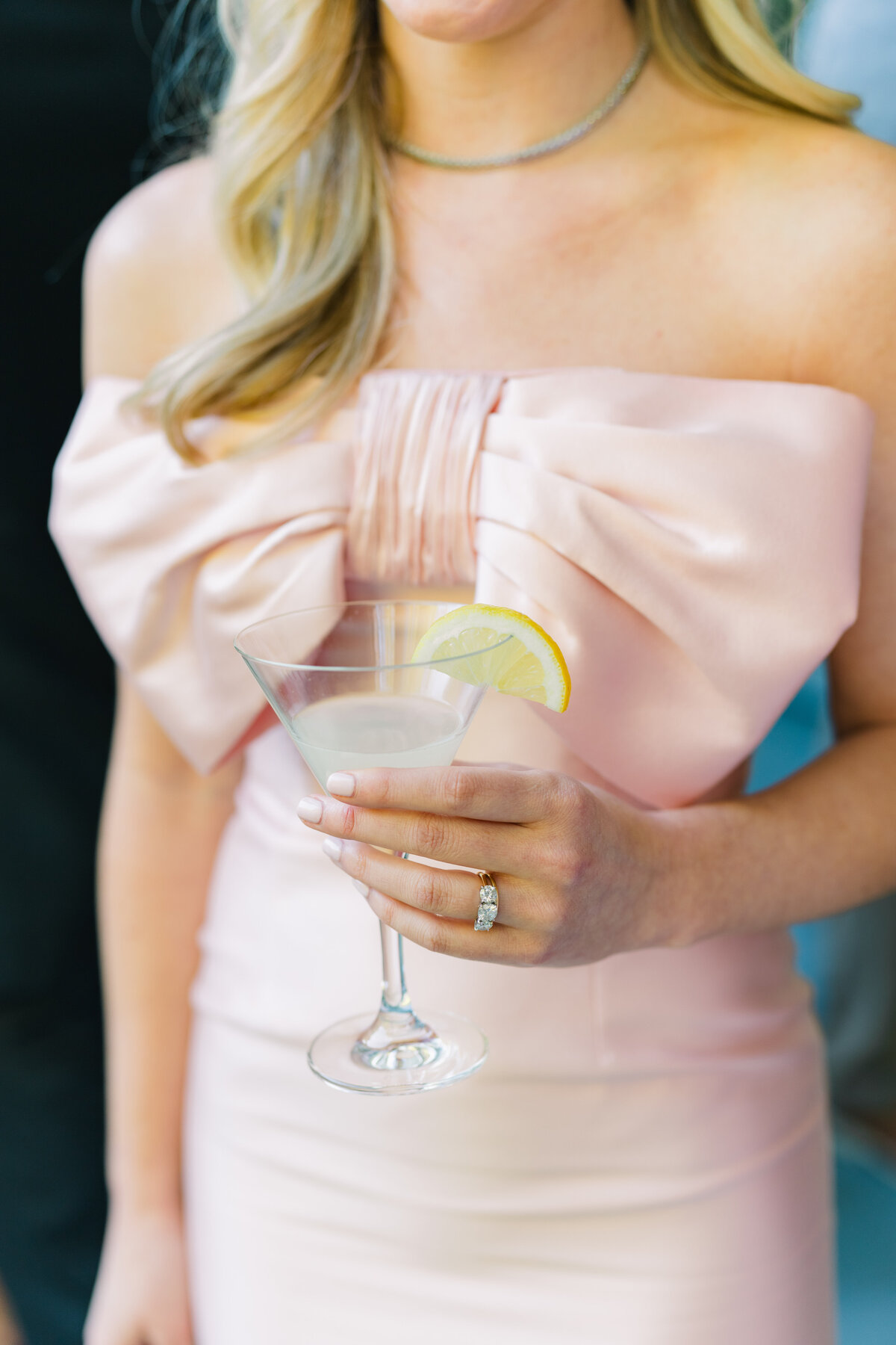 Maid of honor pink dress with large bow on chest. Holding a martini with a lemon garnish.