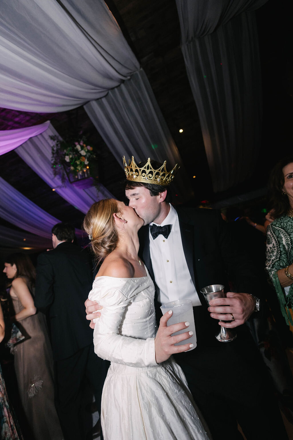 Bride and groom share a kiss on the dance floor as the groom wears a gold crown during their reception at The Bascom in Highlands, NC.