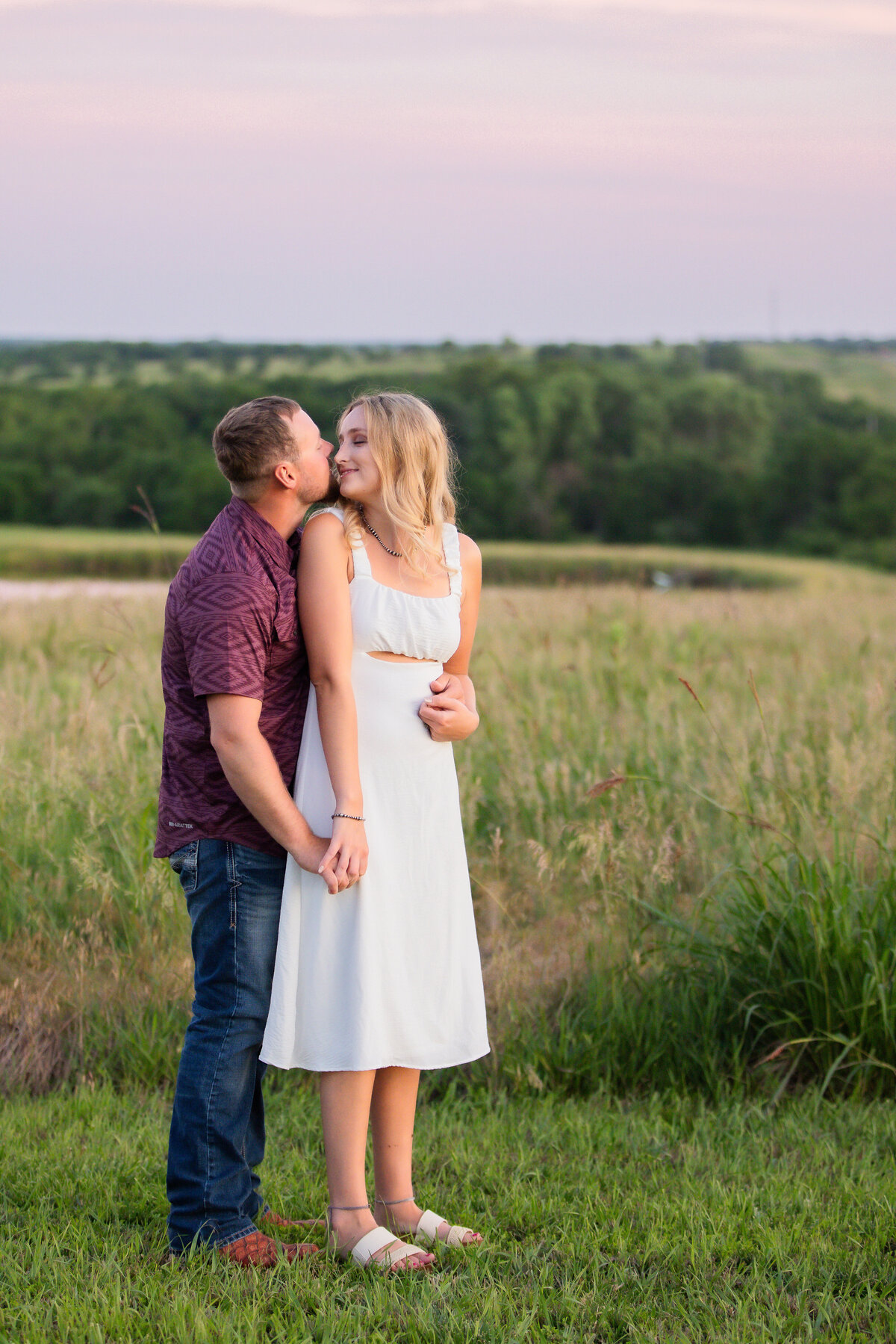 man hugging woman from behind with rolling hills in background