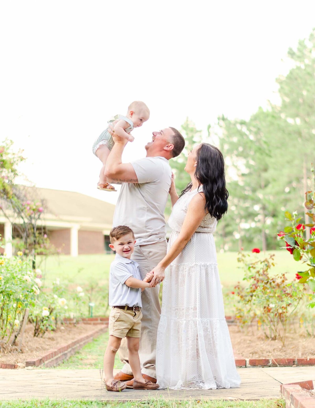 dad throws baby in the air while mom and older boy watch