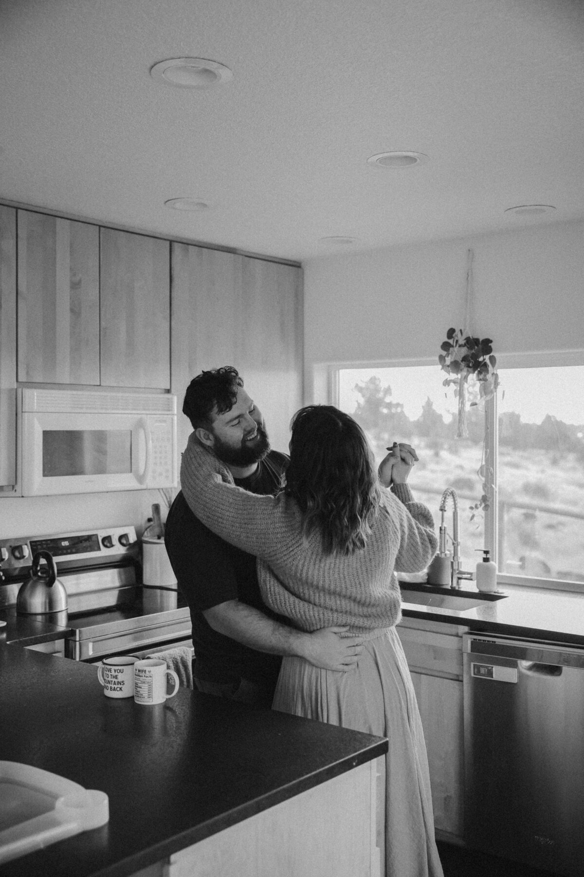 Black and White In-Home Lifestyle Photo of Couple Dancing by Kitchen Window