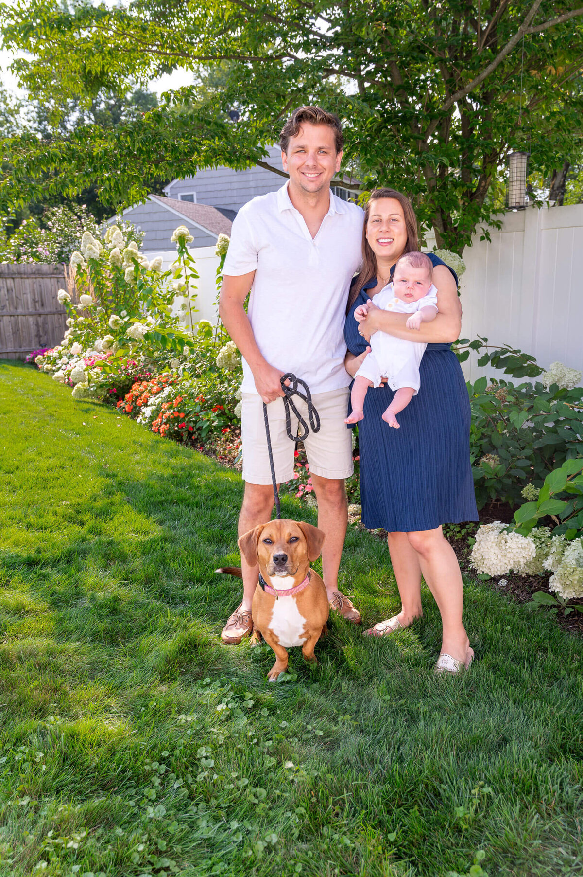 Parents with their newborn baby and dog, in their yard in Cos Cob, CT.