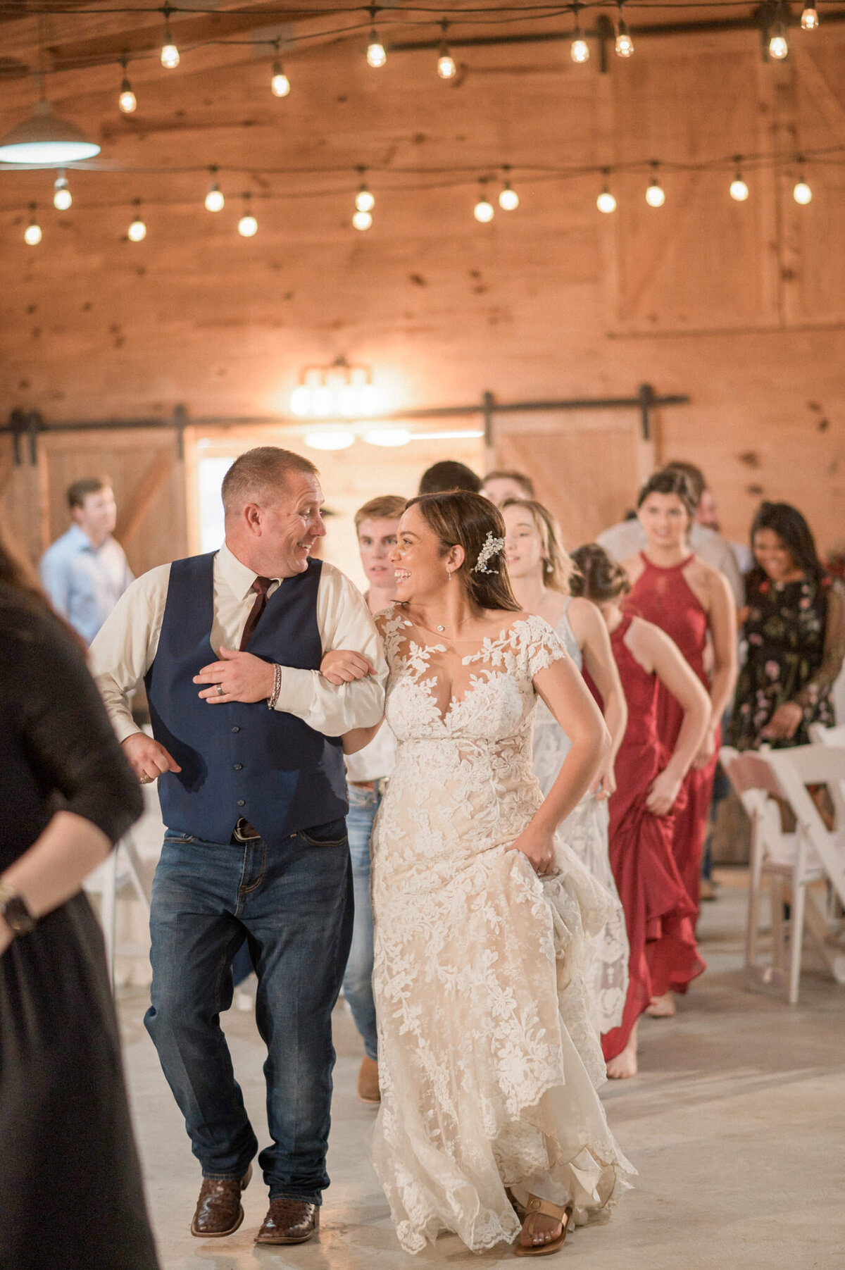 The bride & groom smile joyfully at each other during the grand march as their guests join them on the dance floor during the reception