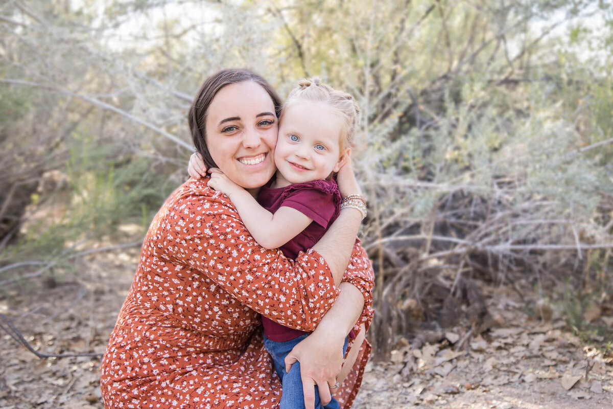 Dark haired mom and redheaded toddler girl hugging in desert park