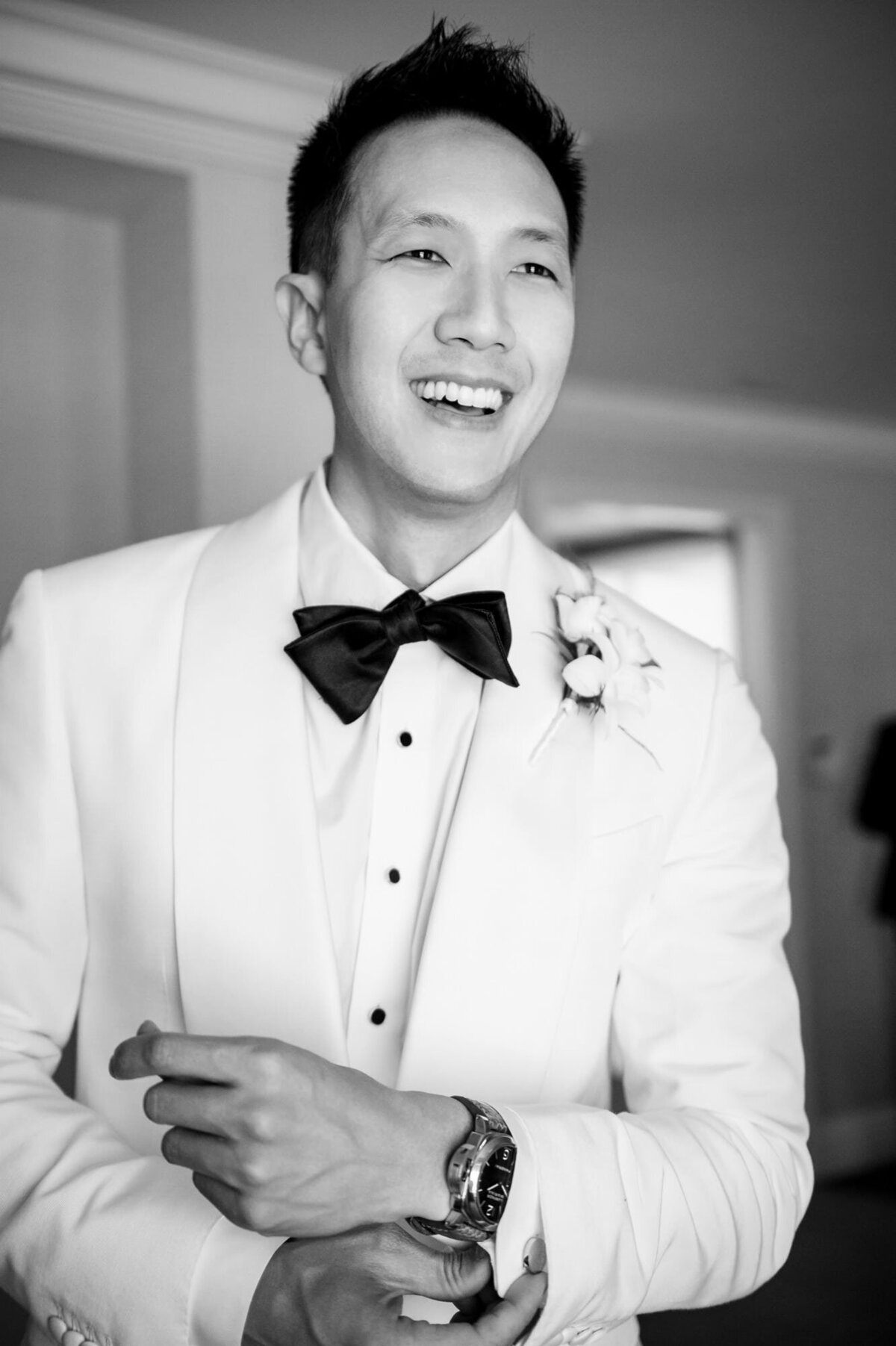 Groom smiling and laughing while he fixes his cuff links