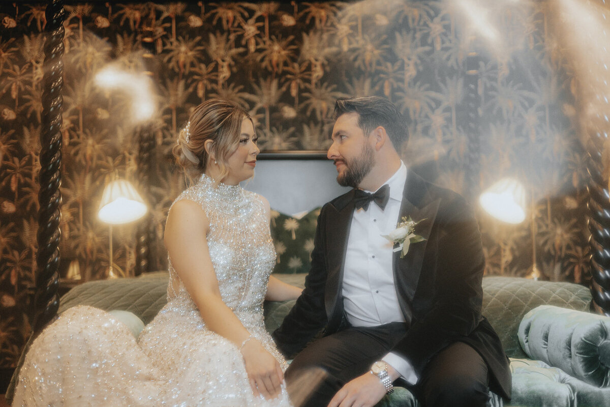 Bride and groom smiling at each other on bed
