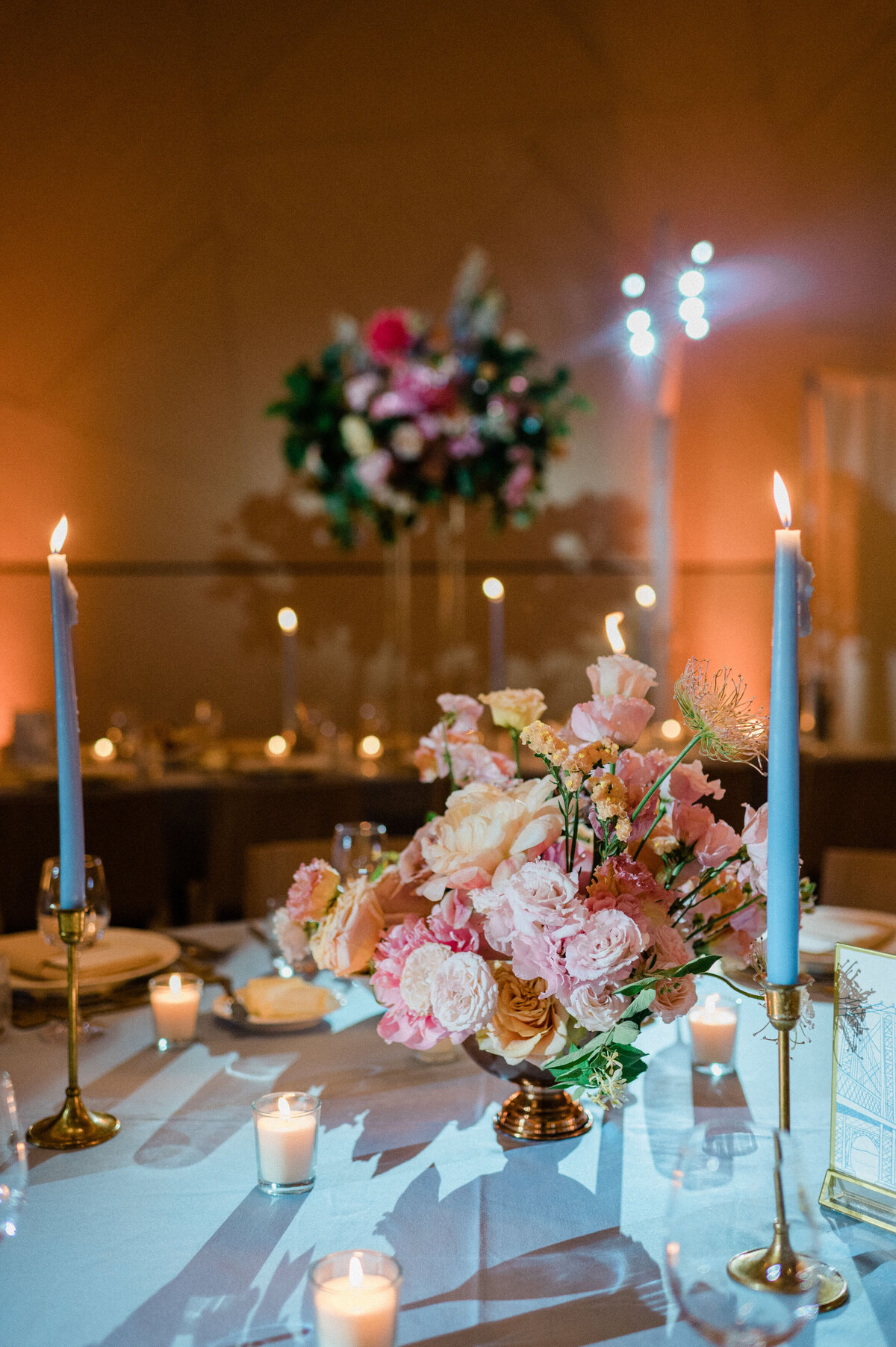 Pink floral arrangement sits on top of a fully set table 