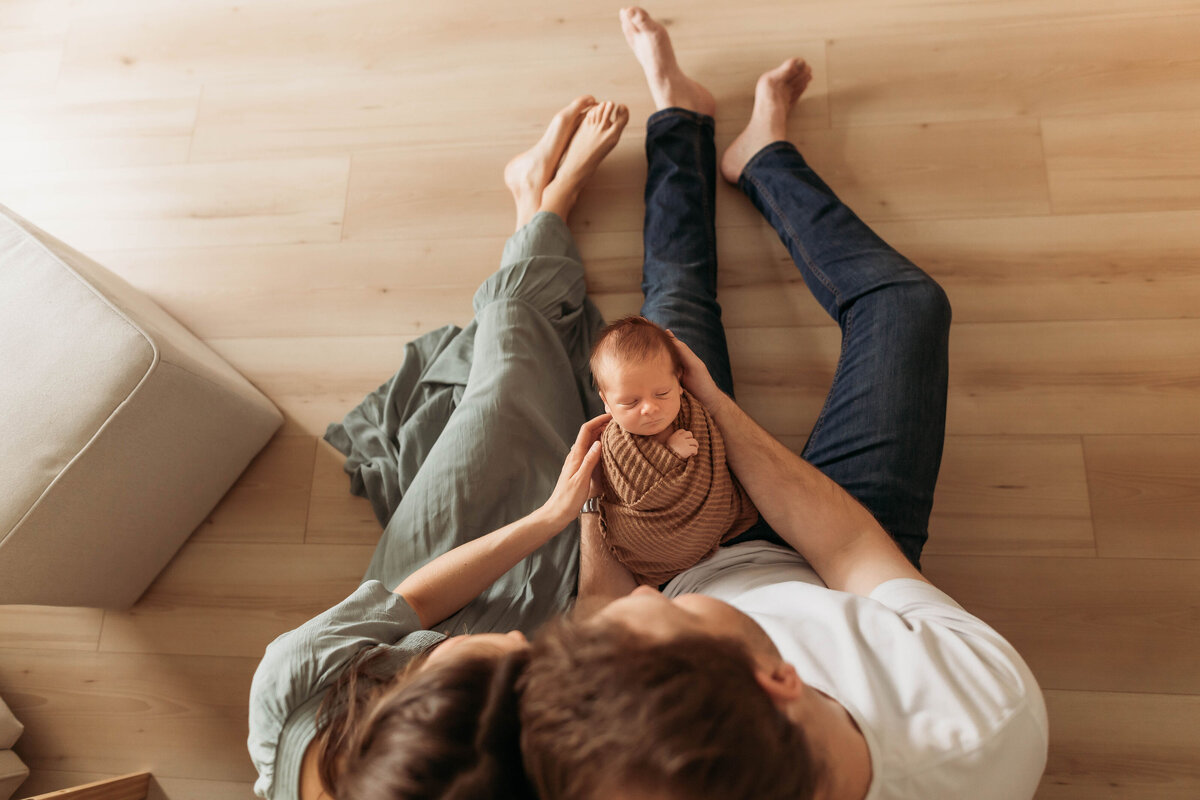 Couple leaning their heads together and admiring their newborn baby.