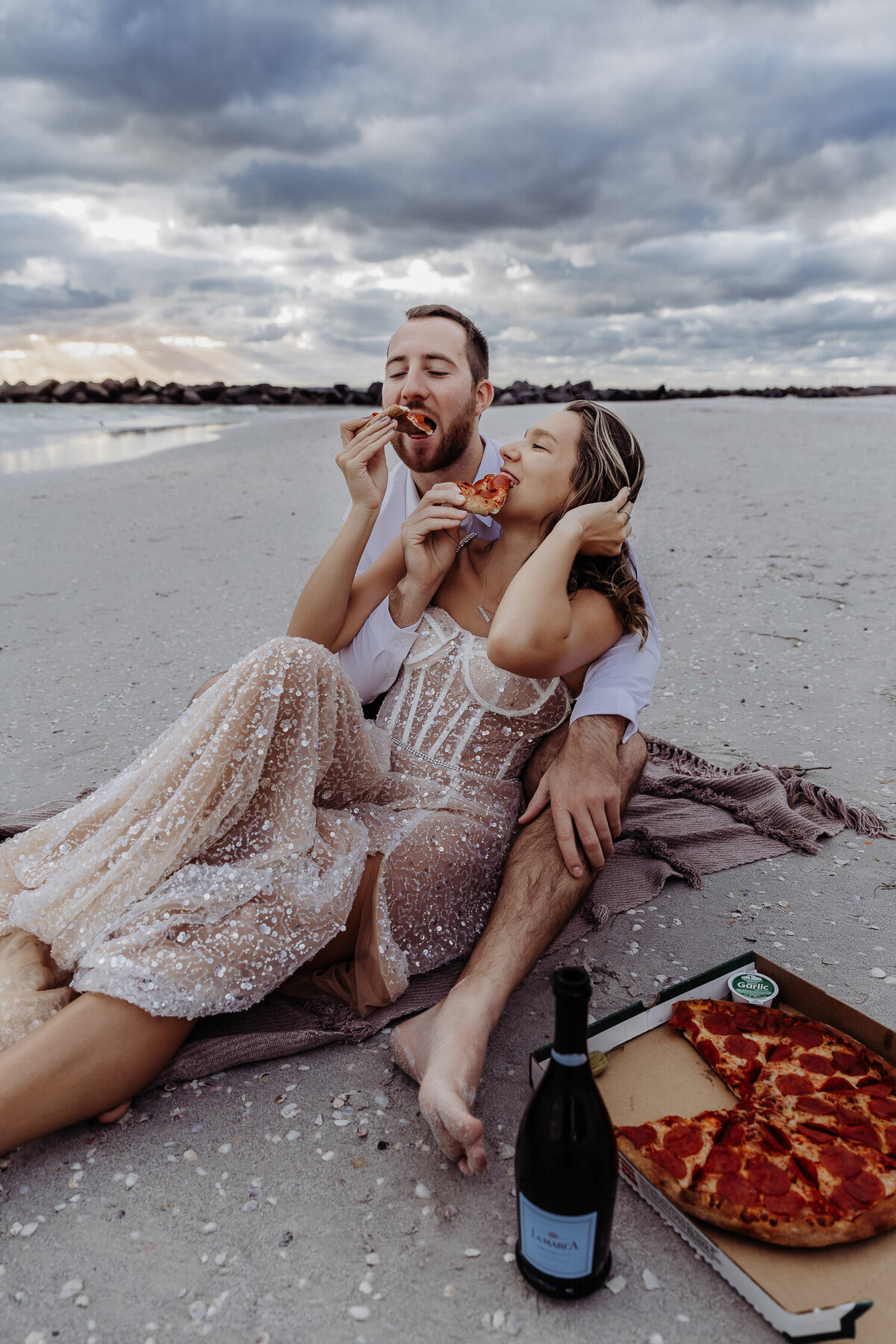 couple eating pizza on their beach during their florida elopement