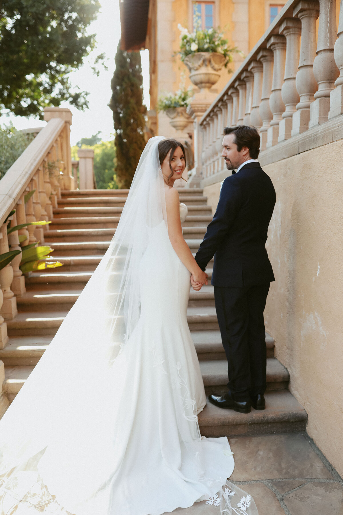 bride and groom standing on stairs holding hands