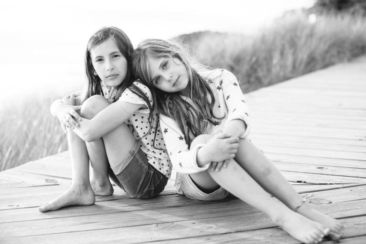 tween sit on pier at beach black and white