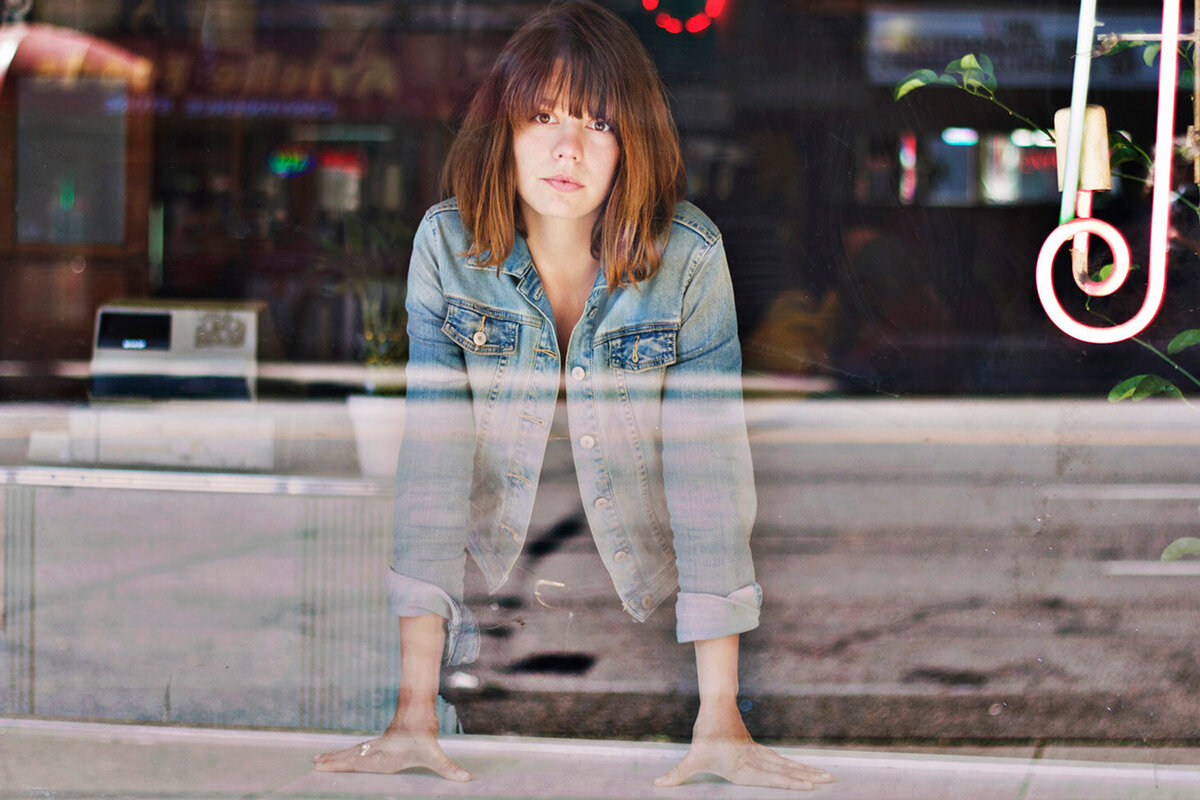 Female musician portrait Steph Cameron standing inside dinner street reflections across window