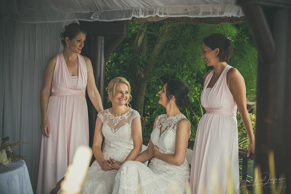 The brides and their bridesmaids sitting and standing with each other