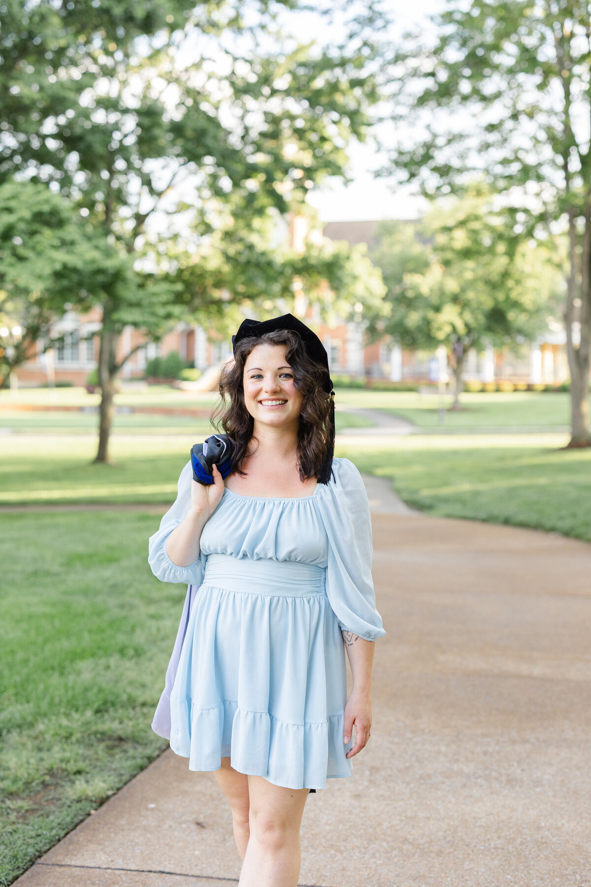 college senior wearing a blue dress and carrying her gown in Cleveland, TN