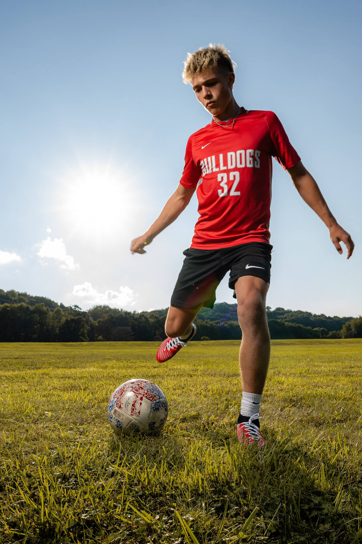 Action photo of a high school senior  kicking a soccer ball in a field near Pittsburgh PA