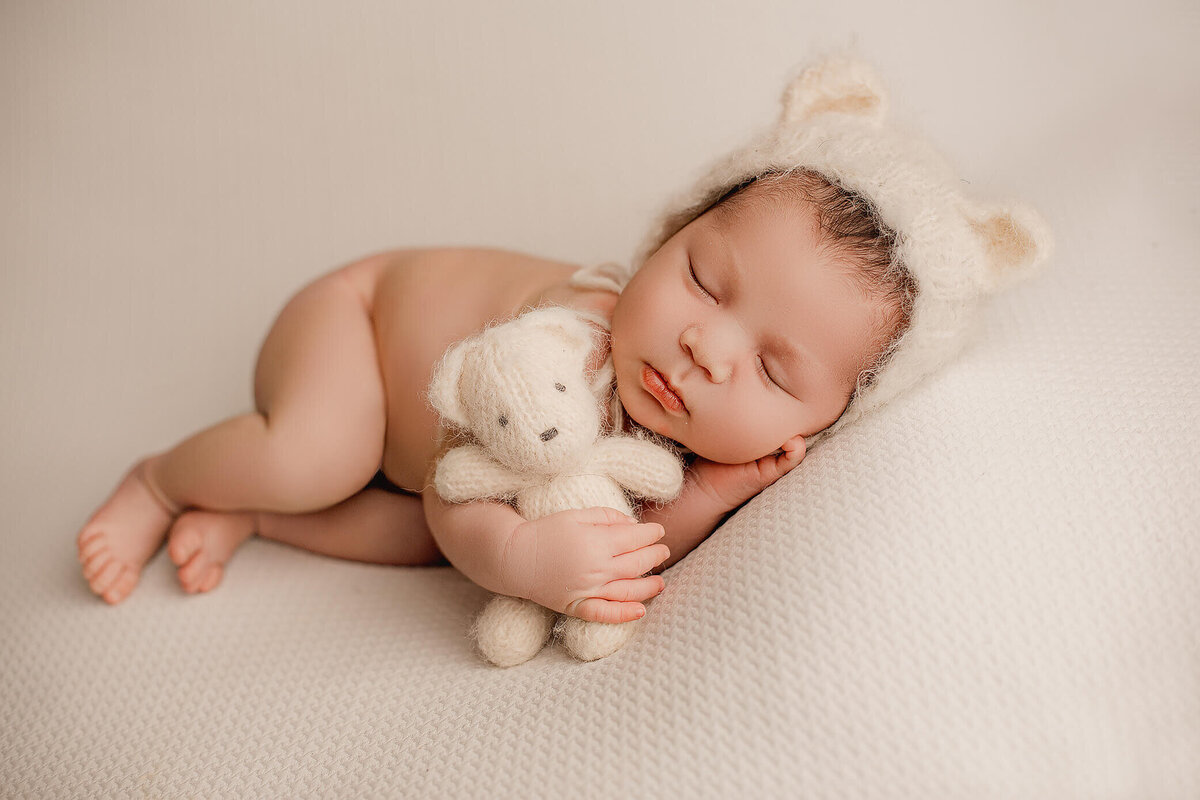 baby boy wears white teddy bonnet during his hamilton, on newborn photography shoot
