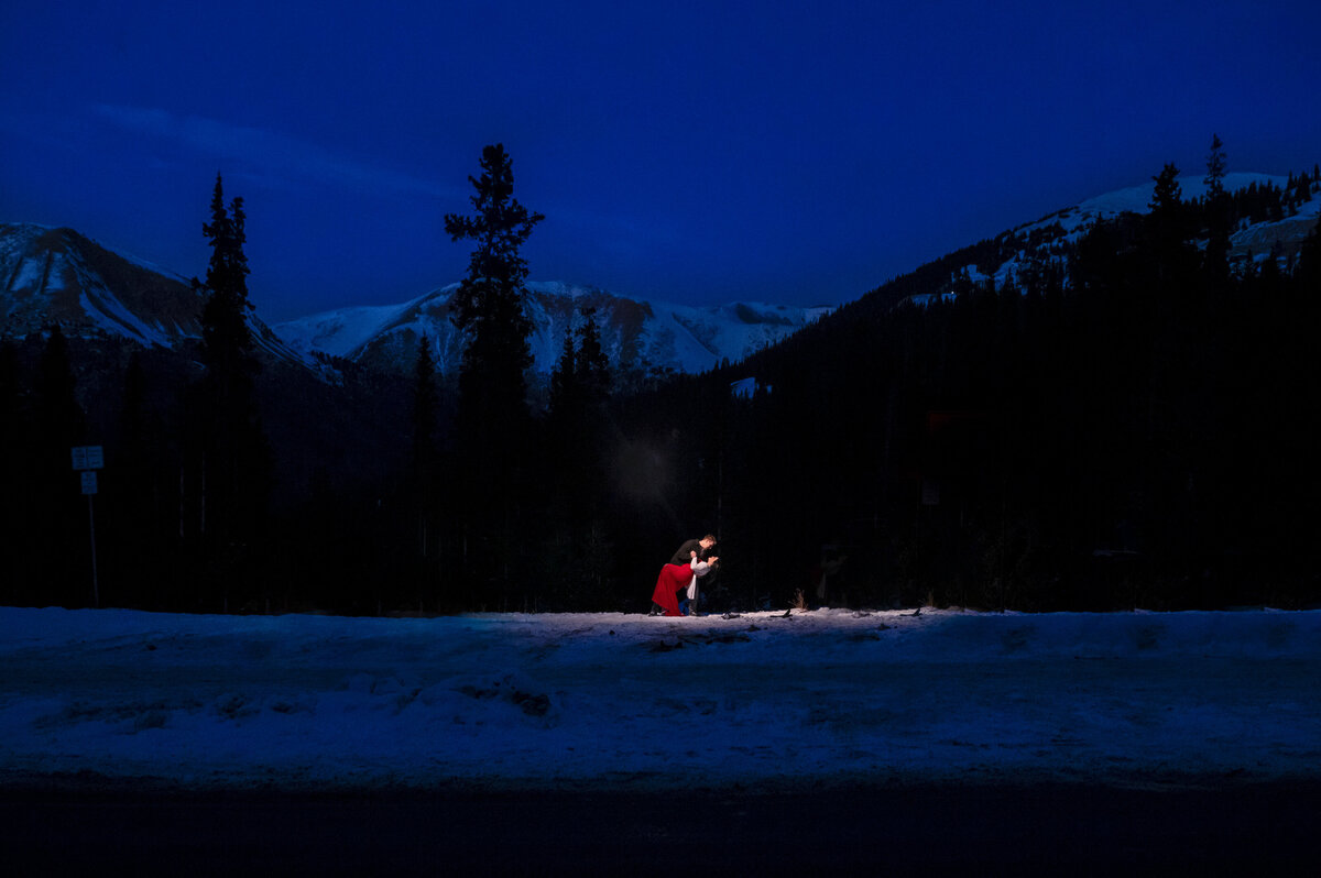 Blue hour engagement photo in the mountains in winter time with snow in a red dress