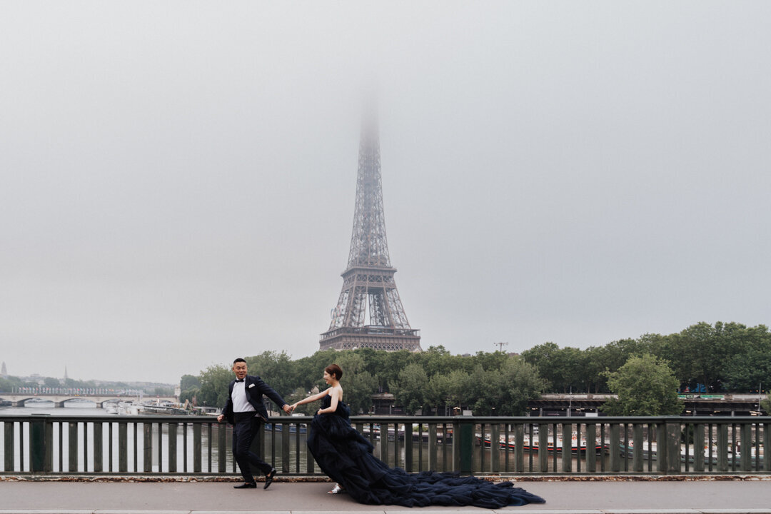 Couple running under Bir Hakeim Bridge Paris, misty morning photoshoot, Eiffel Tower backdrop, candid moment capture