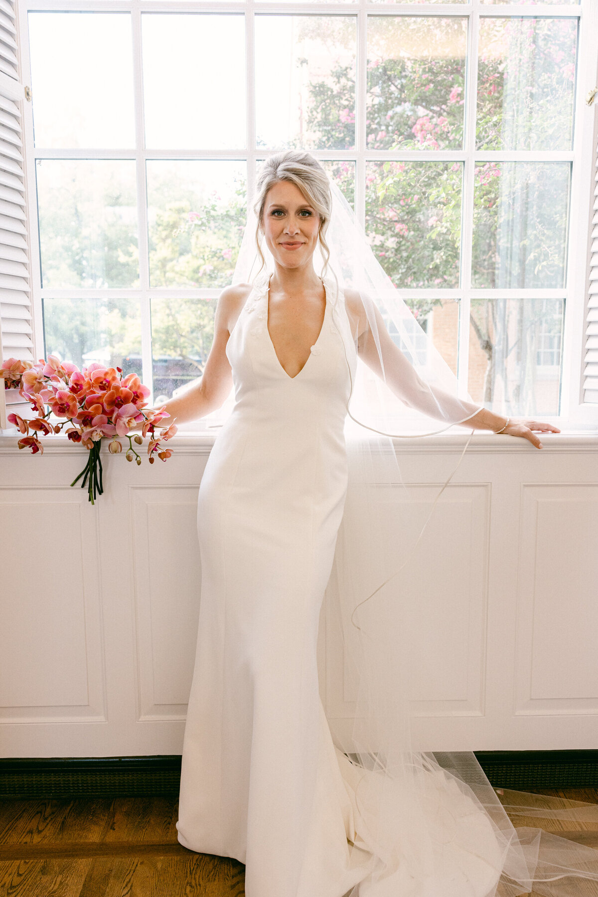 A wedding day portrait photo of the bride looking out a window in the church