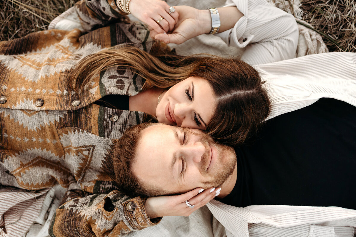 Couple lying in field in Birmingham, AL holding each other's faces.